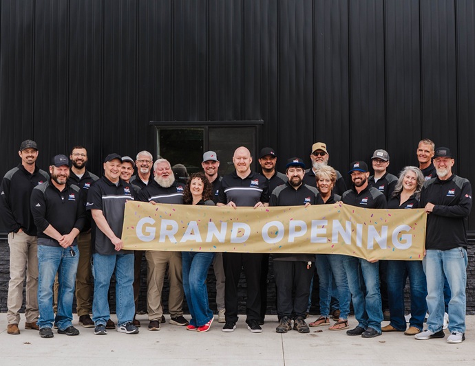 K & E Distributing Team outside the new building with a sign that says Grand Opening